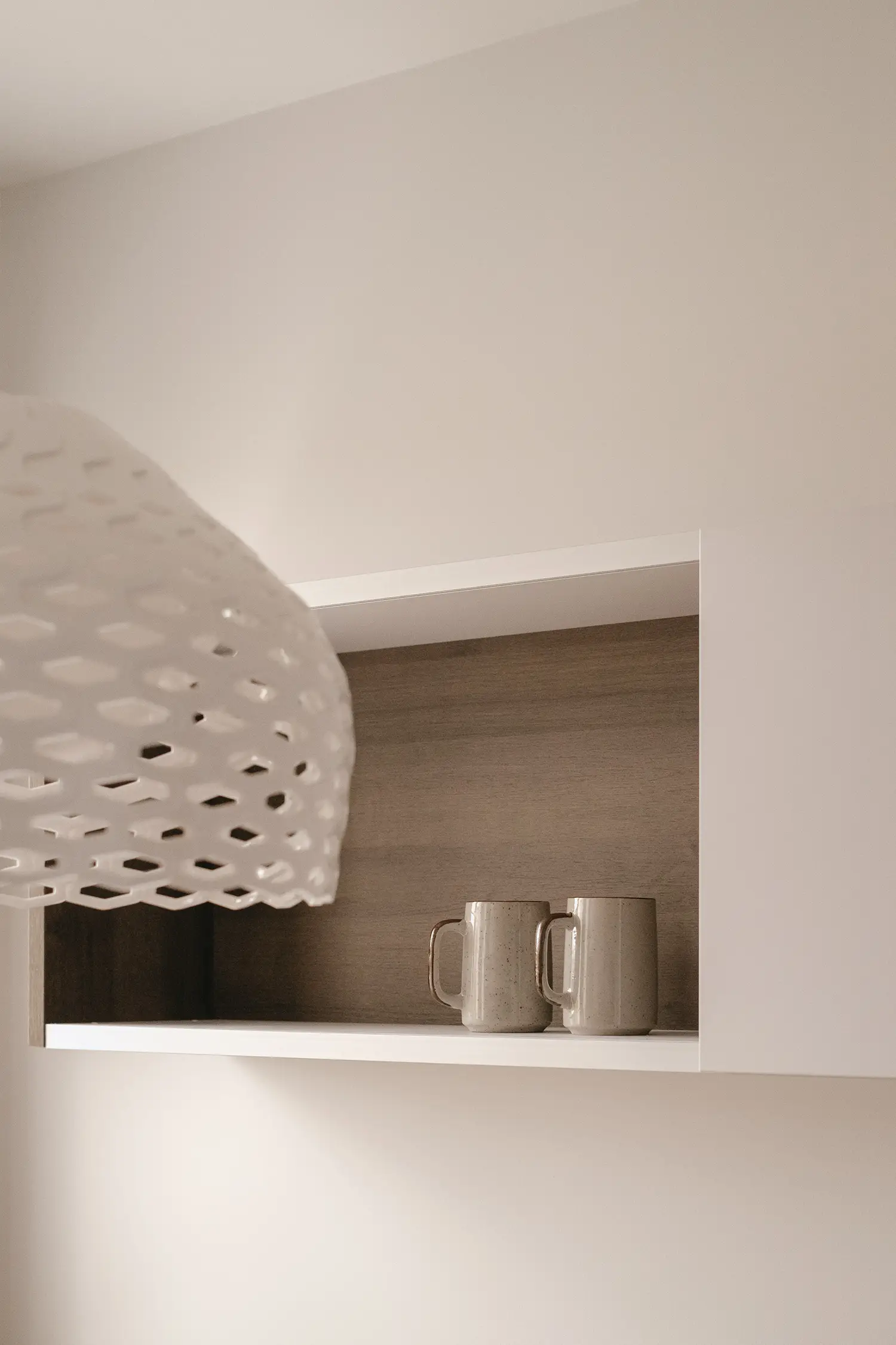 Detail photo of a Flos ceiling light and a white wooden pantry; renovation project by Elles Interior Design.