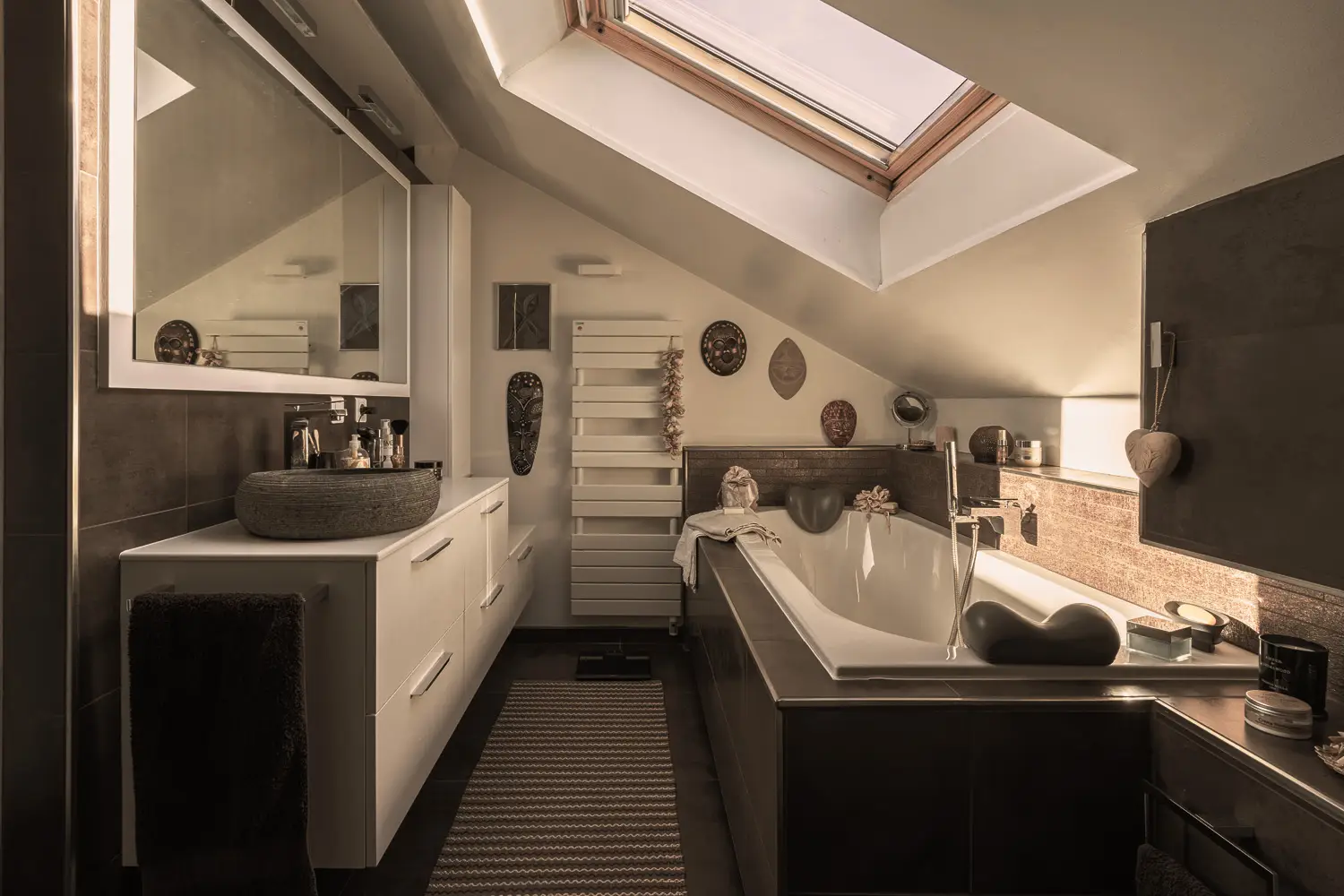 Photo de la salle de bain avec sol et revêtements muraux en céramique dans les tons de bruns, une grande baignoire, un meuble blanc et lavabo en pierre ; Rénovation par le studio Elles Interior Design.