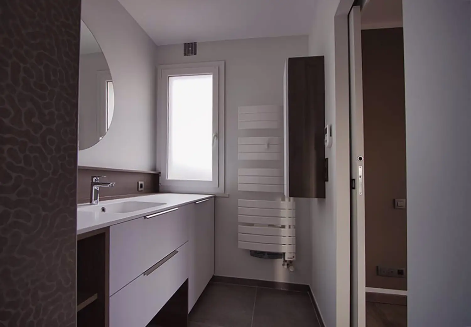 Photo d'ensemble de la salle de bain adjacente à la chambre et accessible par une porte coulissante ; projet de rénovation par le studio Elles Interior Design.