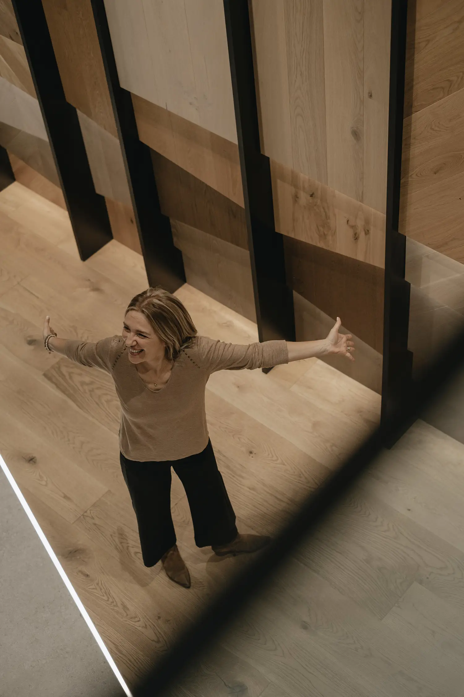 L'architecte d'intérieur Stefania Luraghi est photographiée en train d'écarter les bras devant un élégant panneau de bois.