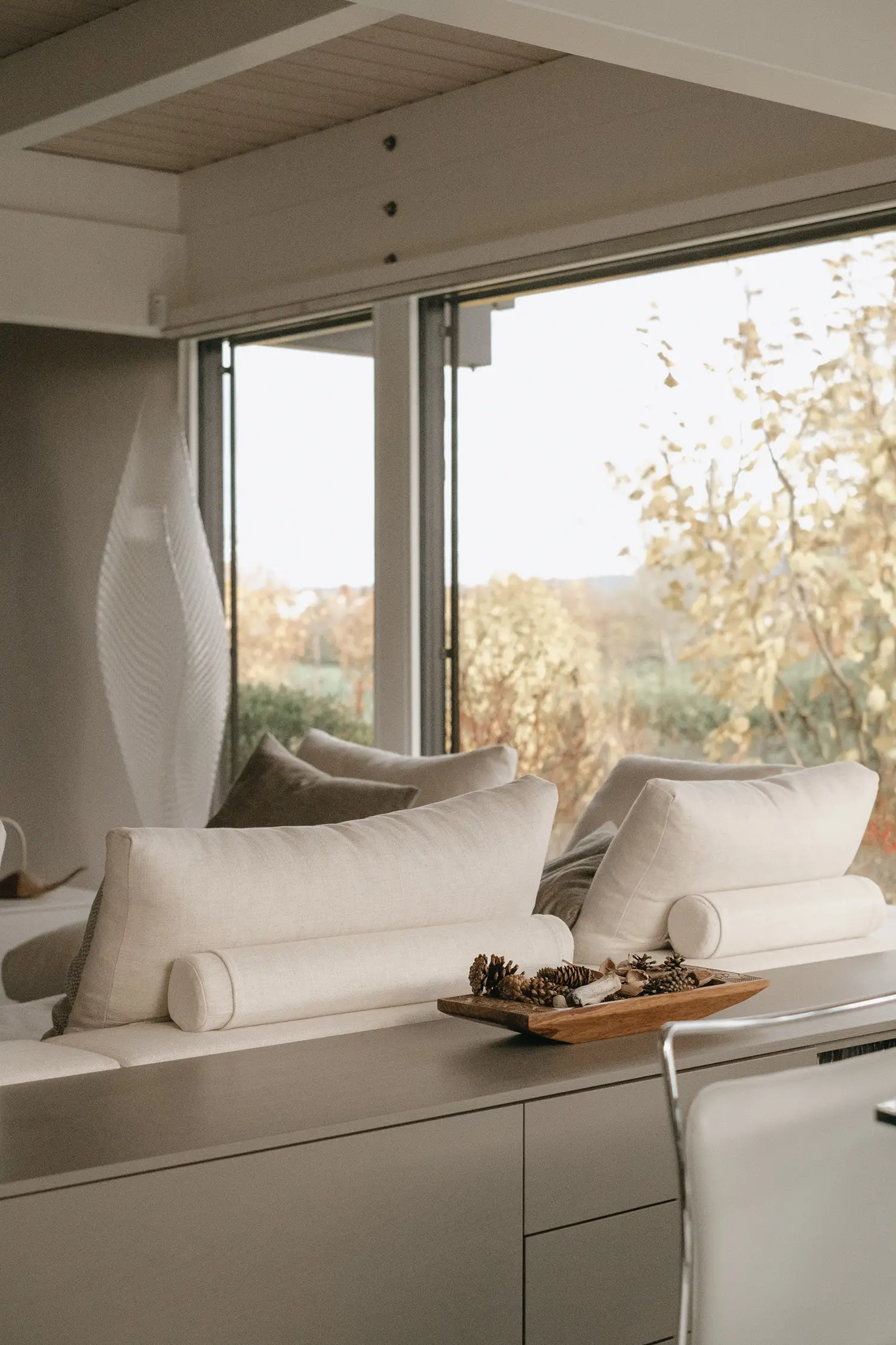 Photo des meubles sur mesure de la salle à manger adossés au canapé du salon ; projet de rénovation par le studio Elles Interior Design.