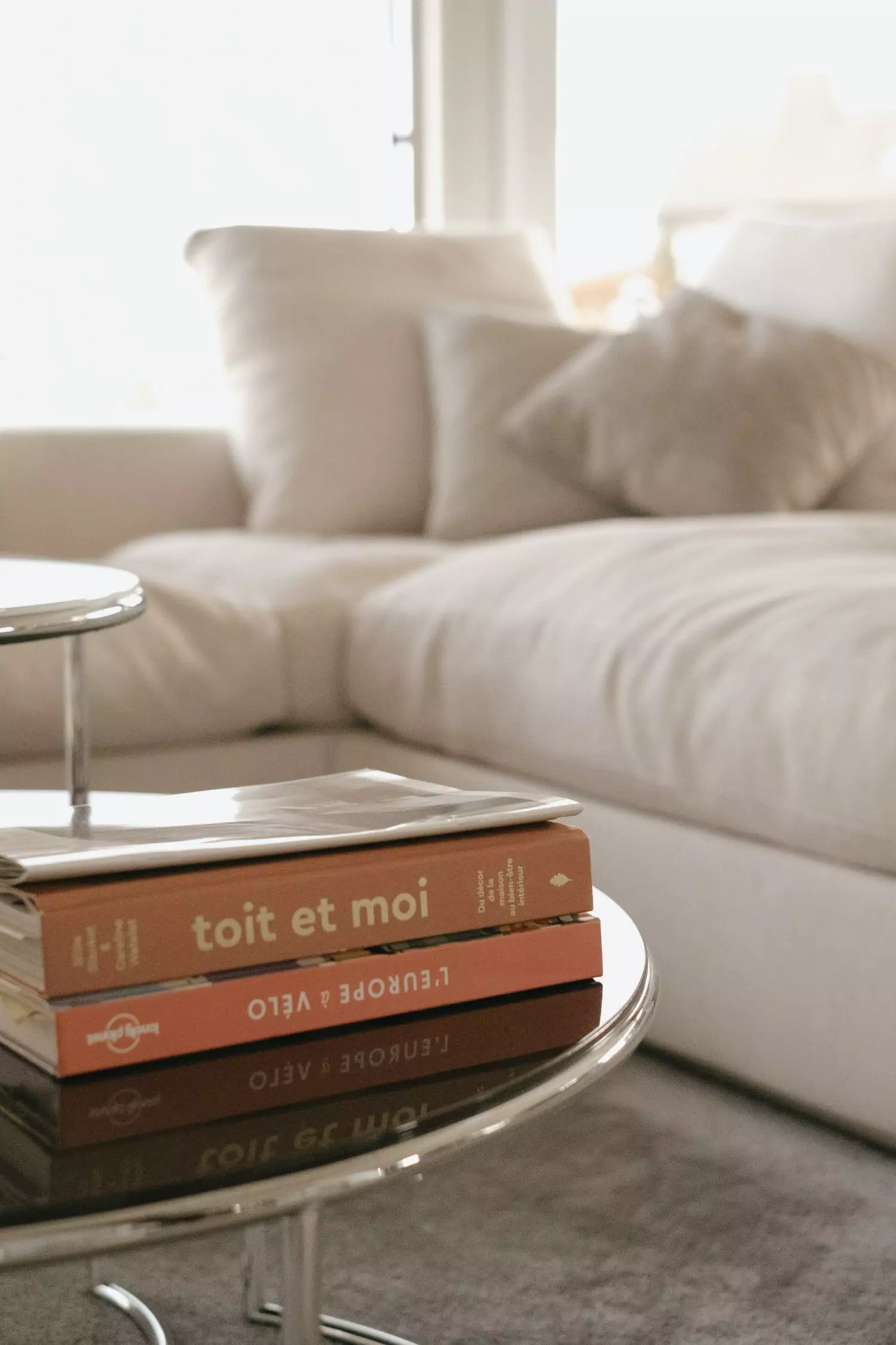 Détail d'un canapé d'angle blanc avec une table basse avec des magazines au centre. Projet de Stefania Luraghi, Elles Interior Design.