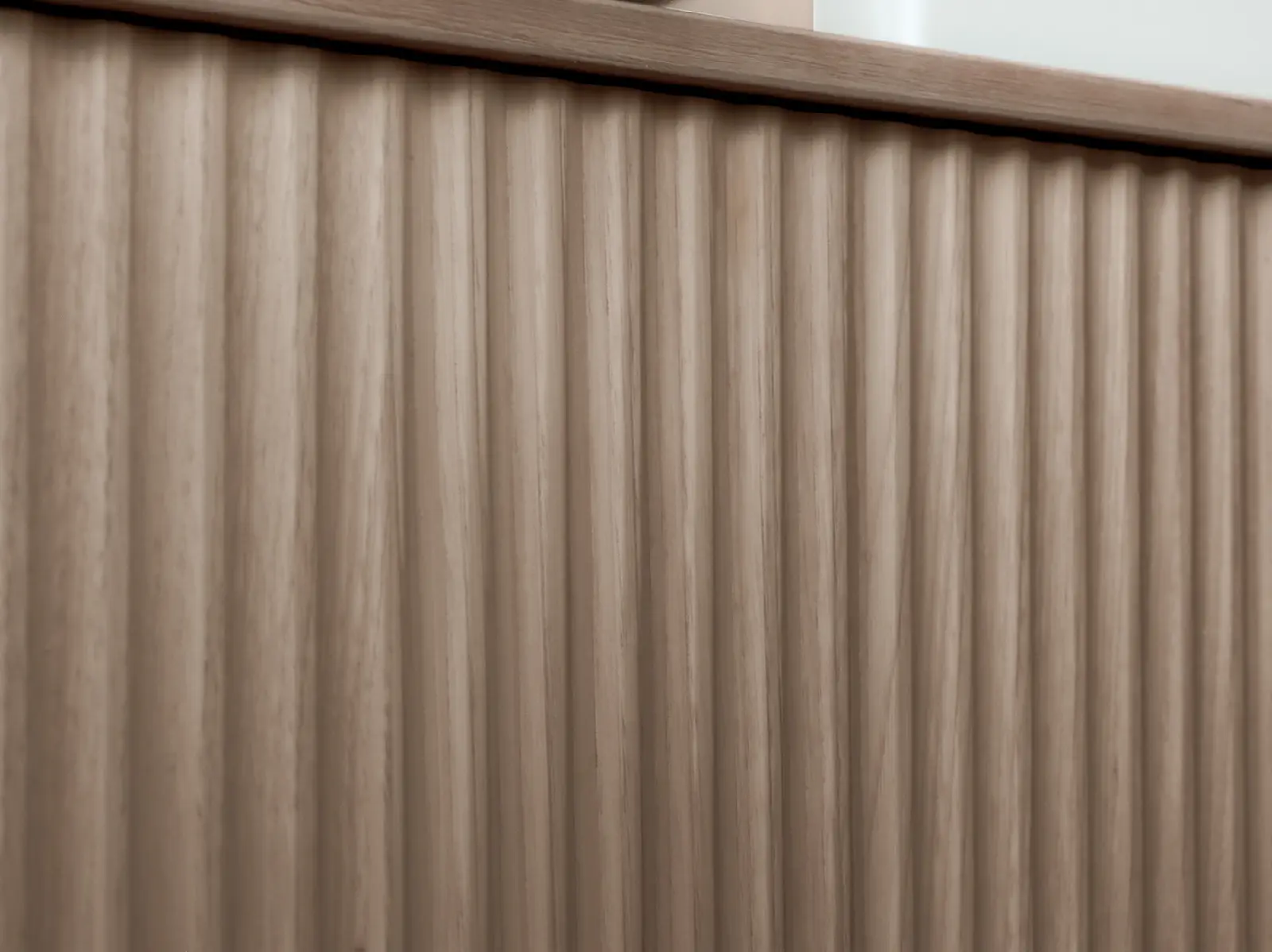 Gros plan des lames verticales rainurées du meuble en bois clair