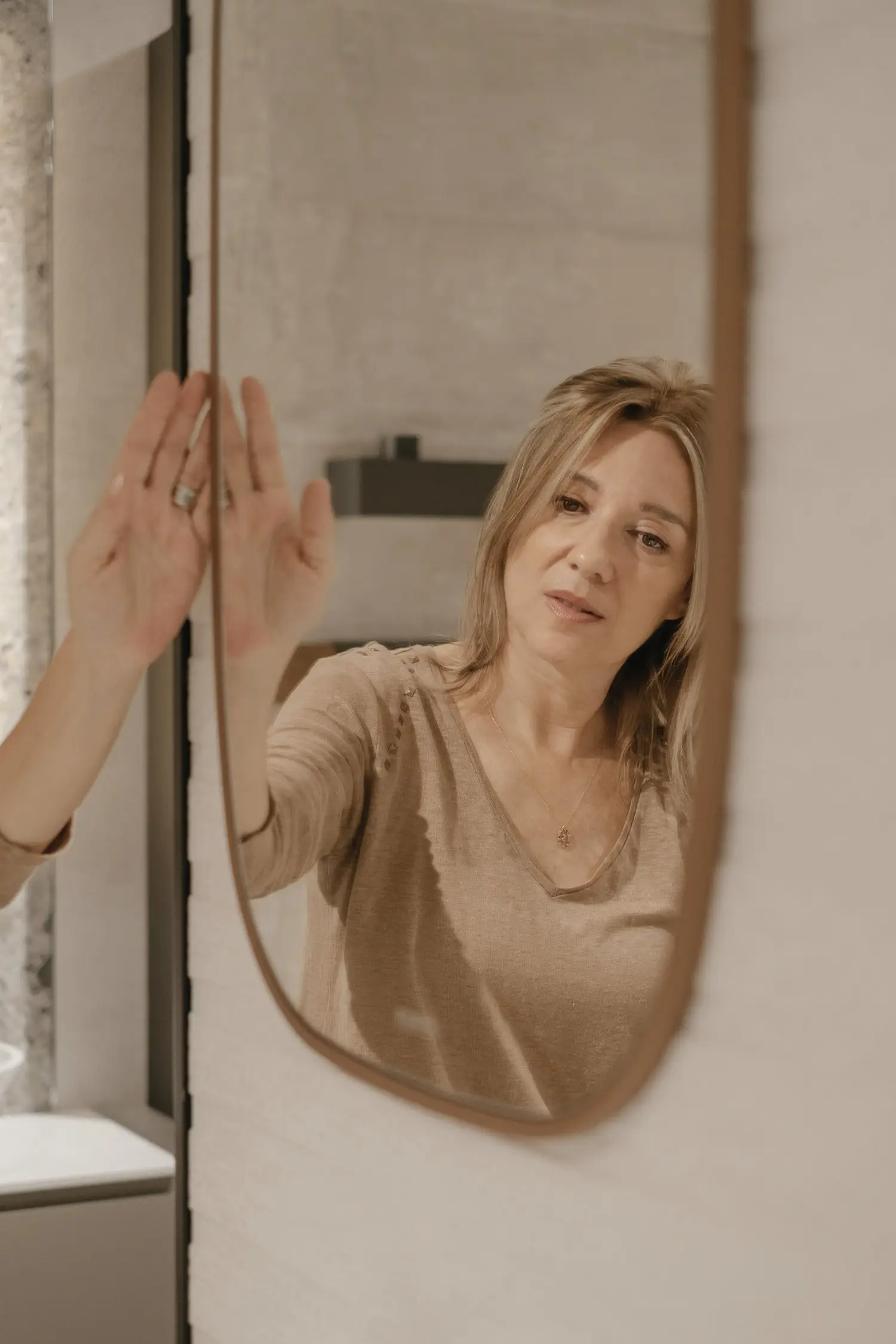 Uno specchio a parete riflette l'immagine di Stefania Luraghi, fondatrice dello studio Elles Interior Design.