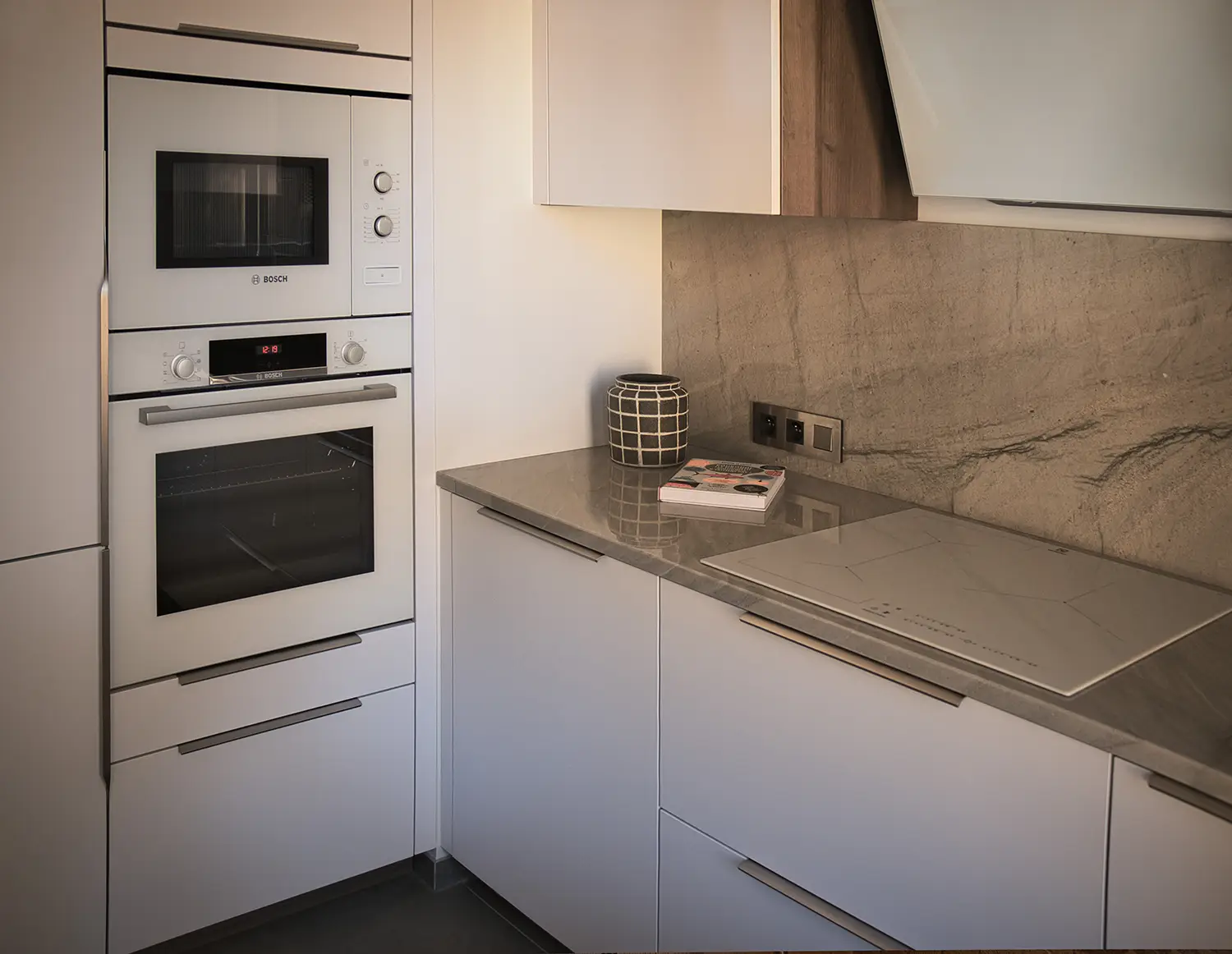 Foto angolo cucina con dettaglio elettrodomestici bianchi per il total look del design con tocchi di legno e ripiano in granito; ristrutturazione dello studio Elles Interior Design.