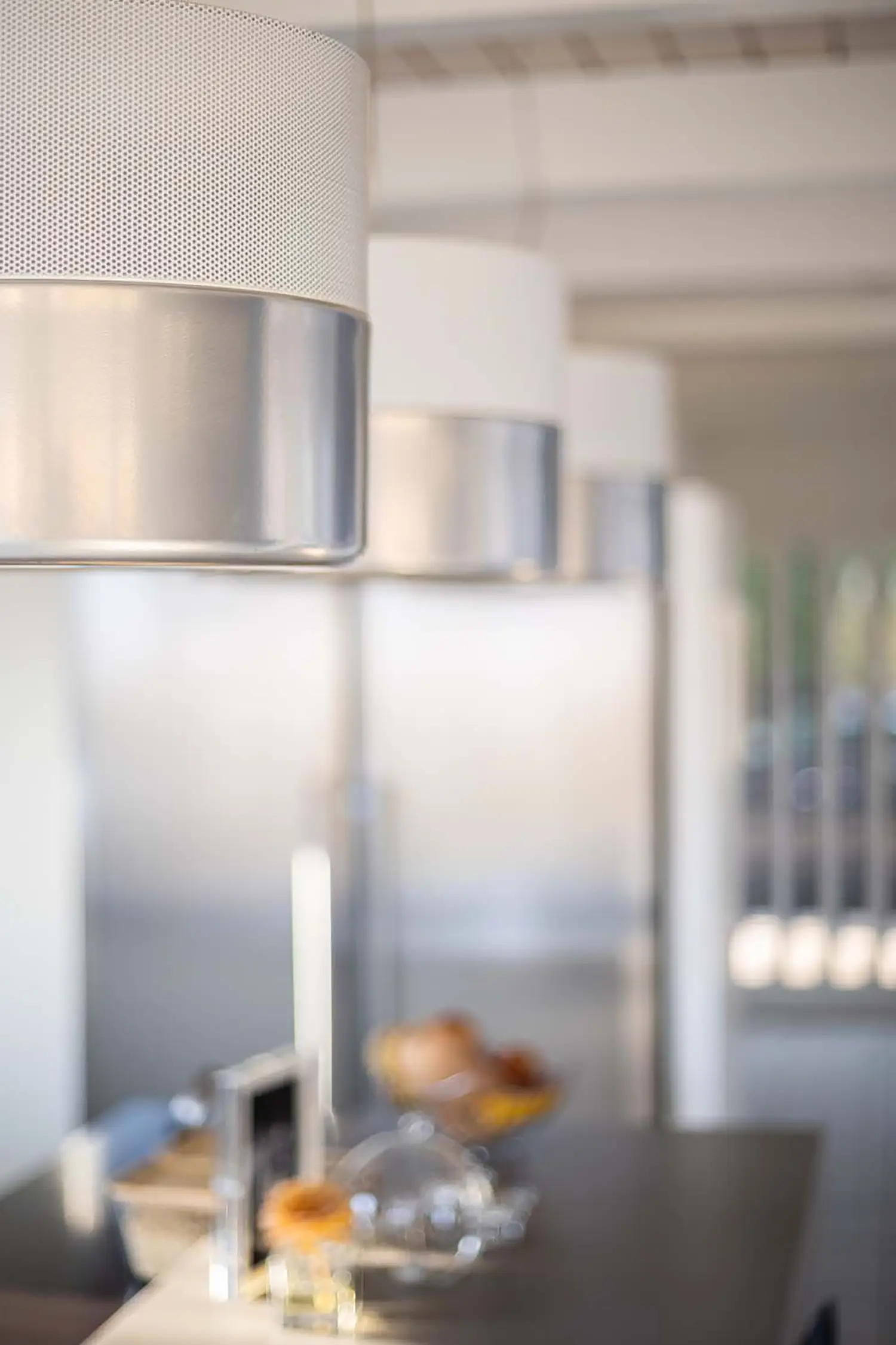 Foto prolungamento isola cucina con dettaglio sull’illuminazione a soffitto di lampade di desing in vetro e metallo, progetto di ristrutturazione dello studio Elles Interior Design.