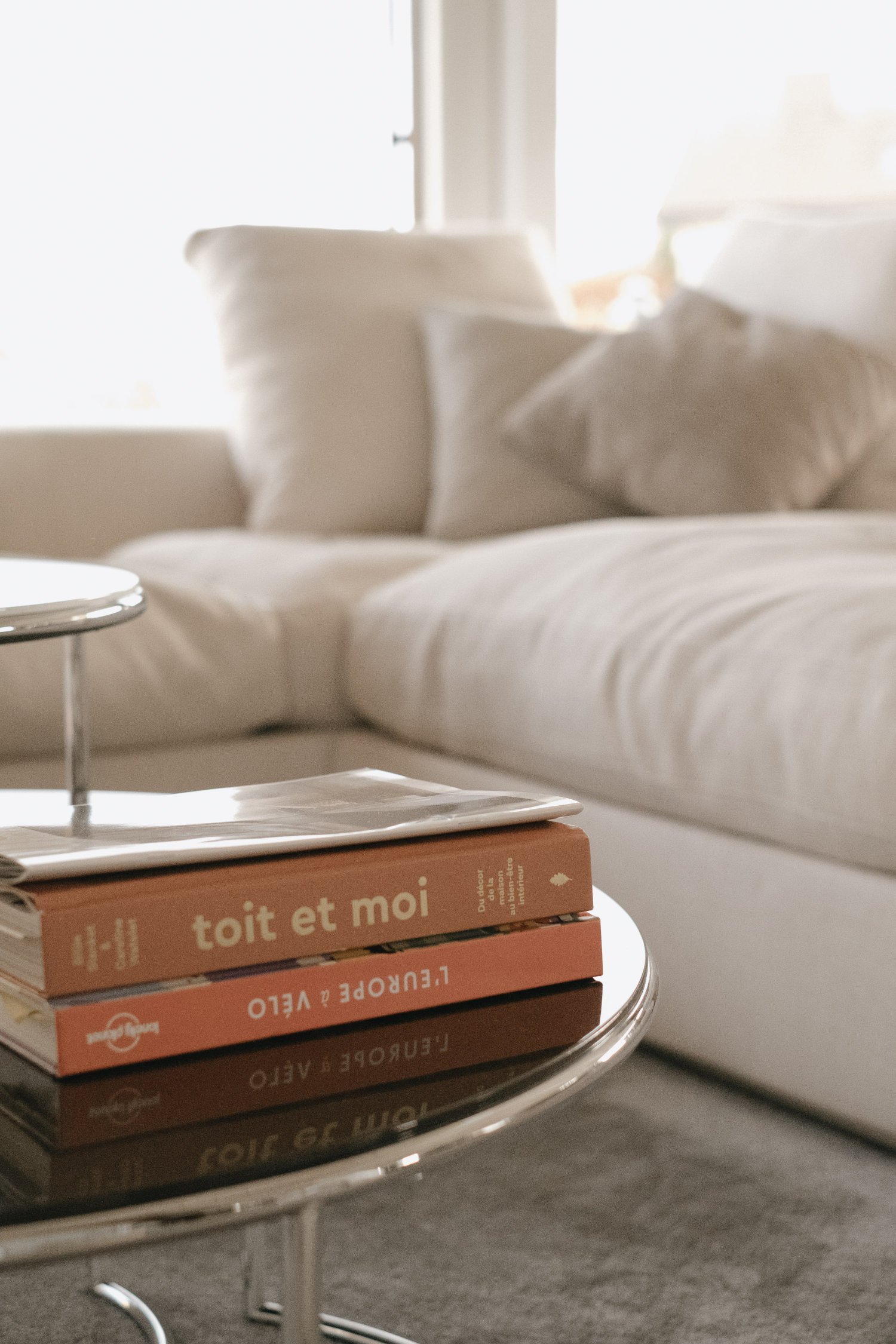 Dettaglio di un divano angolare bianco, che accoglie al centro un tavolino con riviste. Progetto di Stefania Luraghi, Elles Interior Design.