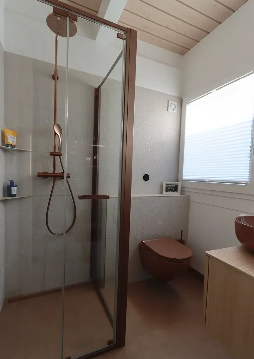 Vista completa del bagno con doccia a filo pavimento, WC sospeso e finestra